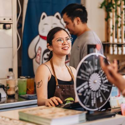 A vendor behind a counter, looking ahead and smiling.