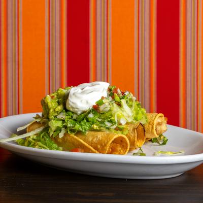 Chicken taquitos, topped with lettuce, tomato salsa, quacamole, and sour cream.