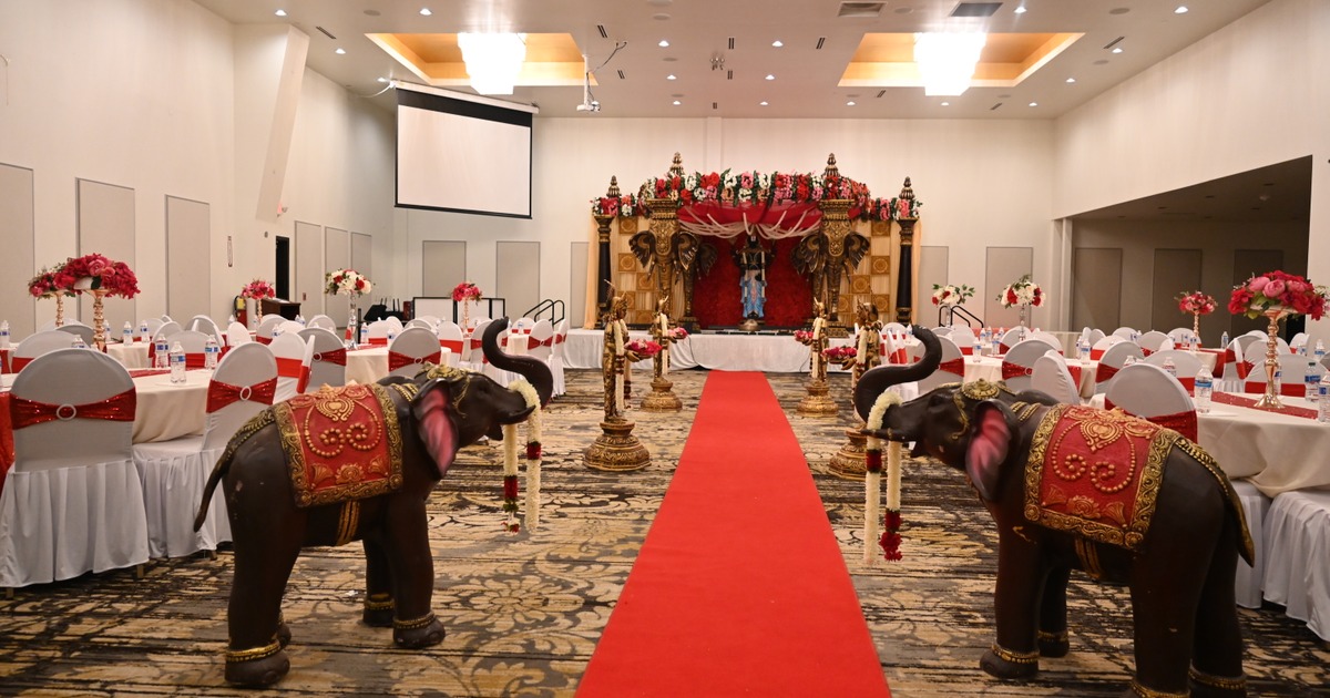 A banquet hall set up for a wedding, featuring traditional decor and a red carpet entrance