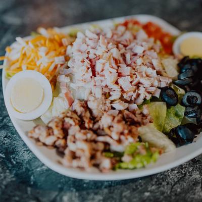 Chef salad with ham, turkey, black olives, eggs, and cheese.