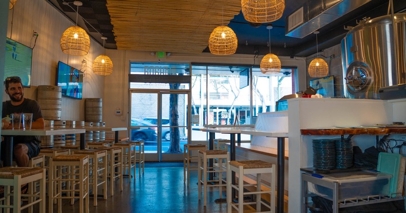 Interior, high-top tables and chairs, rattan light fixtures, and brewing equipment