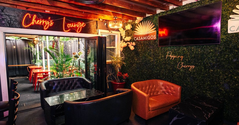 Interior, lounge area, two seater sofas with marble coffee tables, green wall with TV