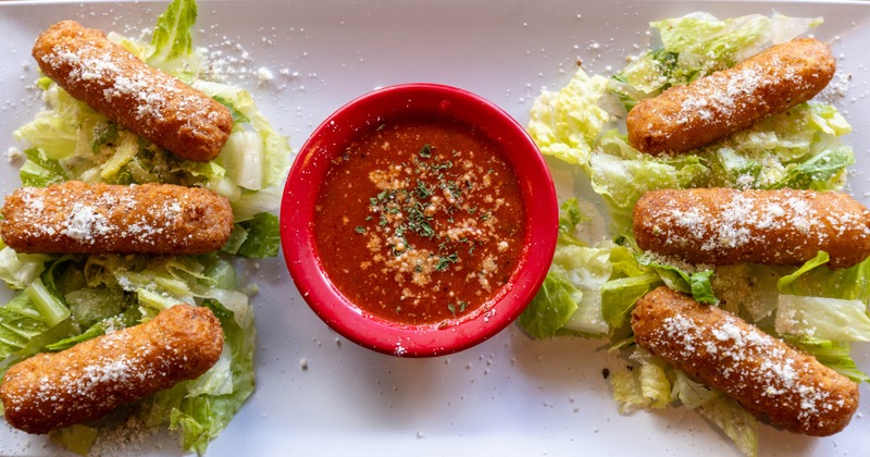Mozzarella sticks served on a bed of lettuce with marinara sauce