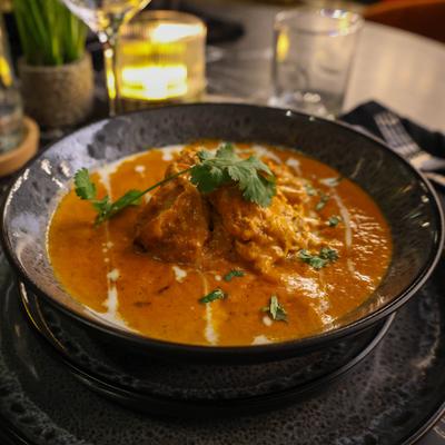 Butter Chicken garnished with cream and fresh cilantro.