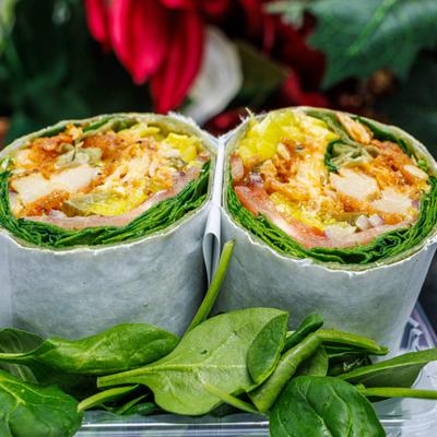 Chicken Wrap served with fresh spinach on the side.