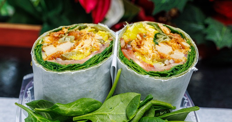 Chicken Wrap served in a plastic container with fresh spinach