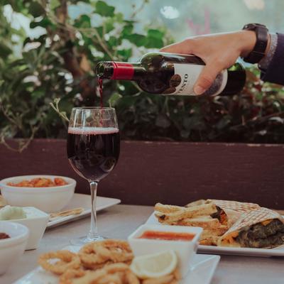 Pouring red wine on the table with served dishes.