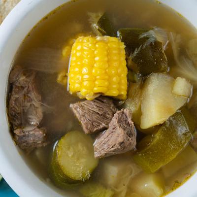 Beef soup with carrots, cabbage, onion, zucchini, cilantro and corn on the cob