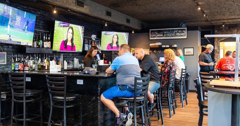 Interior, guests sitting at the bar, bar staff in action