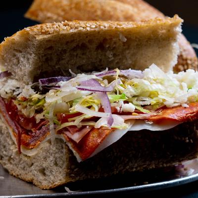 Italian sandwich with cured meats, red onion, and shredded lettuce.