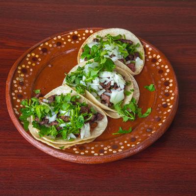 Portion of street tacos topped with diced onions and cilantro.