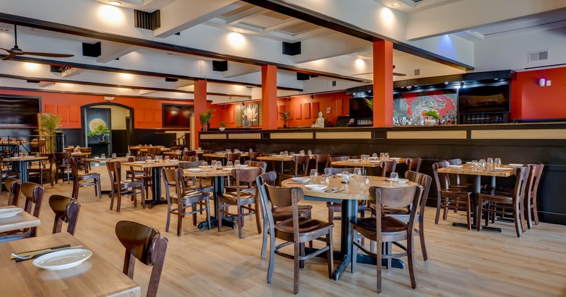 A spacious  interior - wooden tables and chairs, light hardwood flooring and red-orange walls