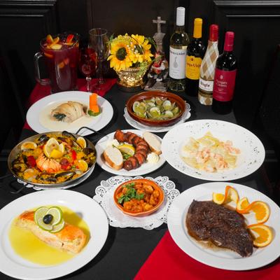 Various dishes served on the table with a flower arrangementa and wine bottles.