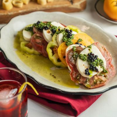 Caprese salad with sliced fresh mozzarella cheese, ripe tomatoes, and olive oil.