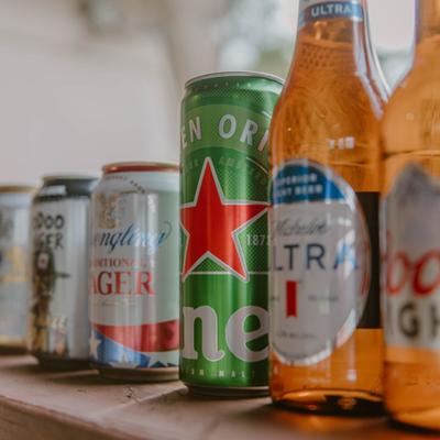 Cans and bottles of beer lined up on a shelf.