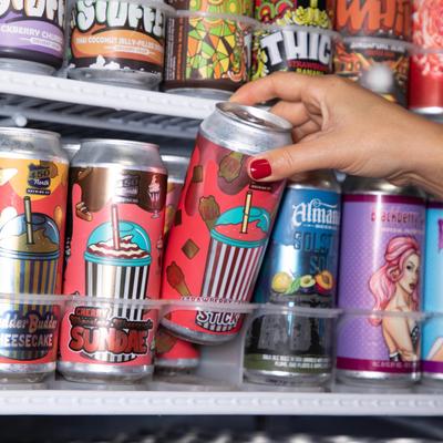 Various soda cans, a hand picking one can up