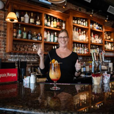 A smiling person behind the bar.