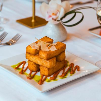 Polenta fries with shaved Parmesan and sauce drizzle.