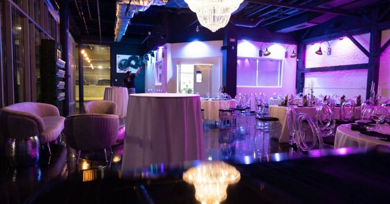 A room bathed in purple light with tables for gatherings