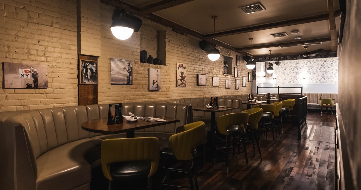 Interior of a restaurant with light brown booth seating, yellow green chairs, and wall art