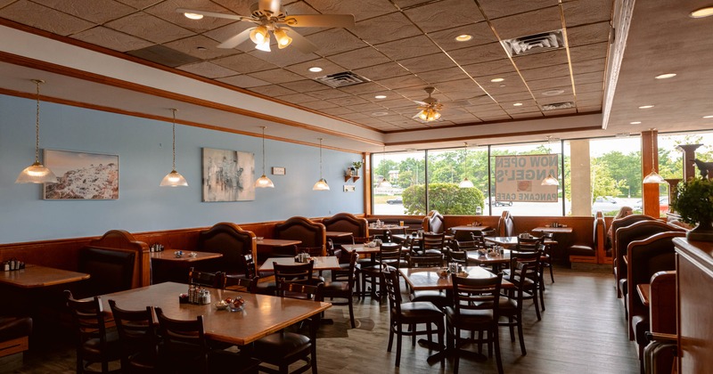 Interior, dining area, booths, tables and chairs ready for guests, large windows in the back