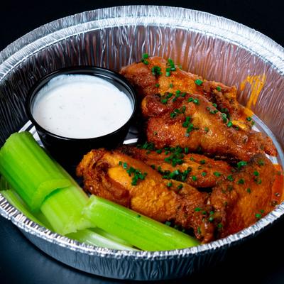 Chicken wings topped with chopped chives served alongside celery and dipping sauce.