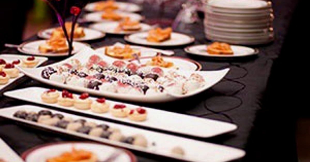 Buffet table with various finger foods, canapés, and a stack of white plate
