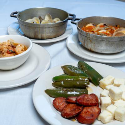 Cheese and sausage plate on the table with  sauteed shrimp dish, red clams, and yellow clams.