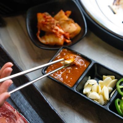 A hand holding chopsticks above various foods.