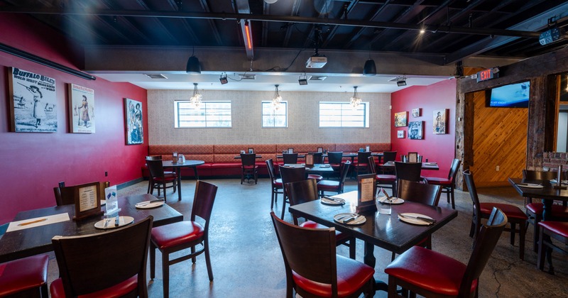 Interior of a restaurant with red and beige walls, bench seating, dark wooden tables and chairs