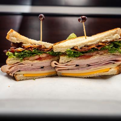 Close-up of a halved turkey club sandwich.