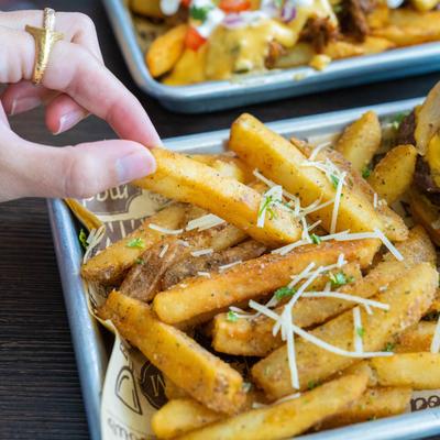 A hand reaches for a seasoned pile of fries.