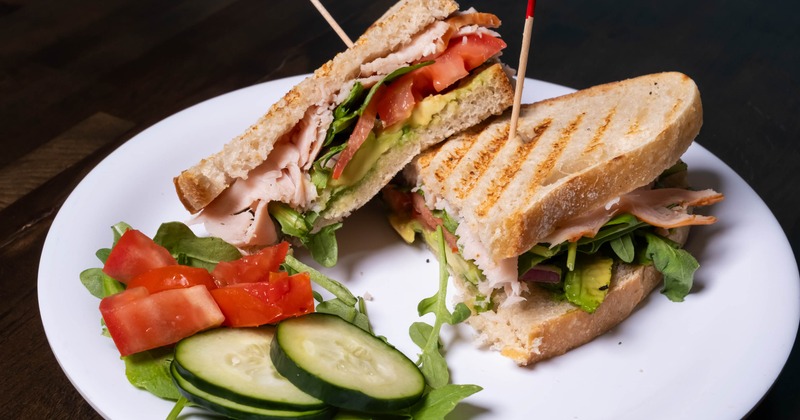 Turkey club sandwich sliced in half and served with fresh vegetables