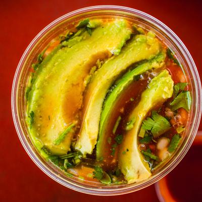 Shrimp cocktail served in a plastic cup and topped with avocado slices, overhead view.