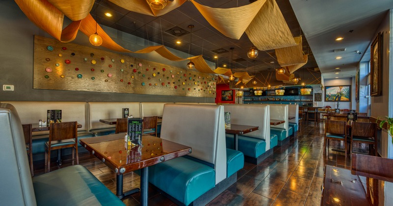 Interior of a modern restaurant with booth seating and wooden wave-like ceiling panels