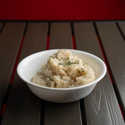 Mashed Potatoes served in a white bowl, garnished with herbs.