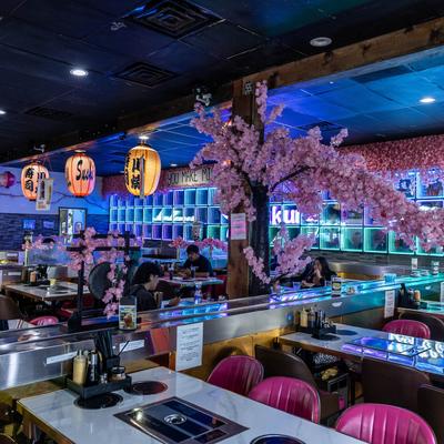 Interior, hot pot tables, pink cherry blossom trees, lanterns, and blue lighting.