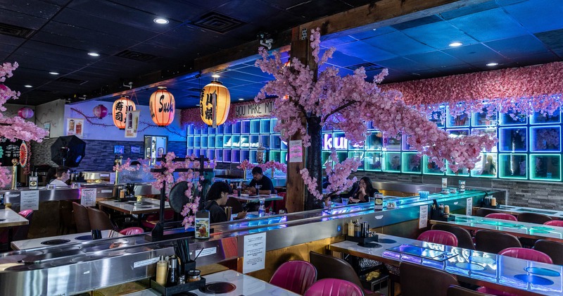 Interior features neon lighting, artificial cherry blossom trees, and traditional lanterns