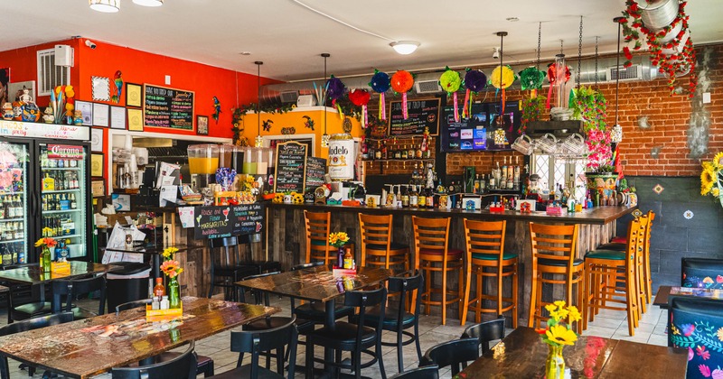 Interior, dining and bar area, tables for four, six and two, bar with stools in the back