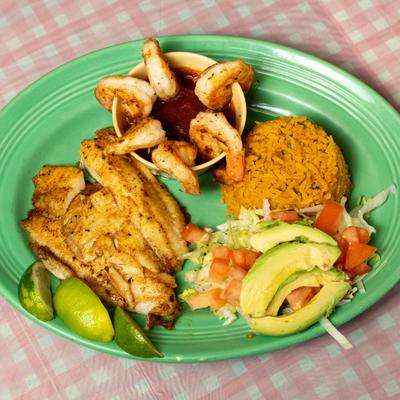 Seafood plate with shrimp cocktail and fish filet served with rice and salad.