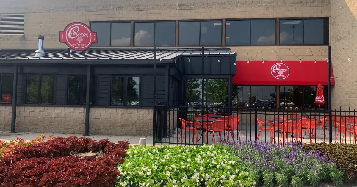 Exterior with fenced patio with table seating and red awning