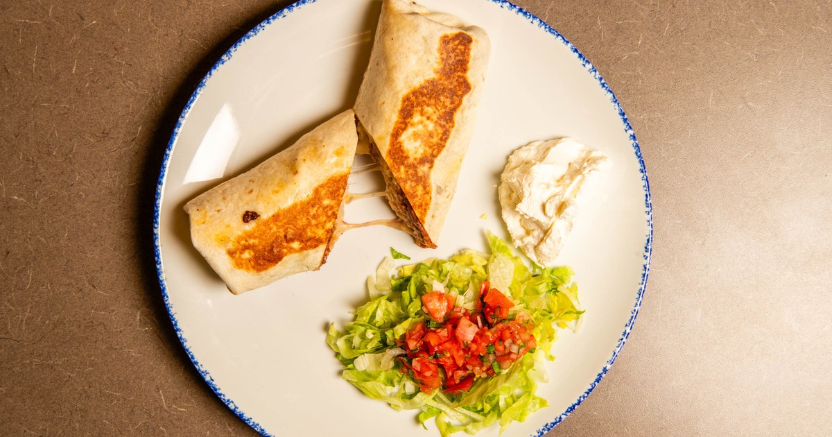 Steak Burrito with salad and sour creme on the side, top view