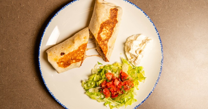 Steak Burrito with salad and sour creme on the side, top view