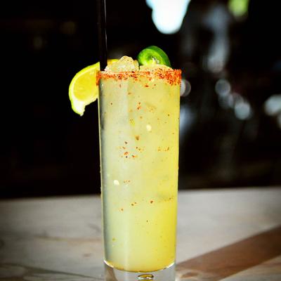 Fuego Margarita cocktail in a glass with spiced rim, lime, and jalapeno garnish.