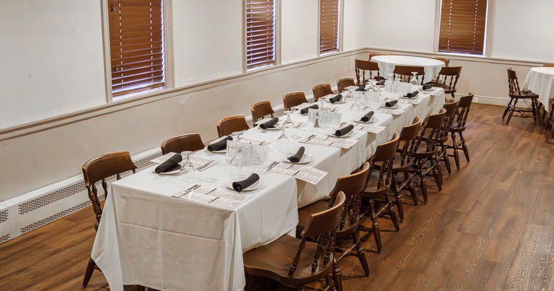 Dining area with a long table with white tablecloths, black napkins and wooden chairs