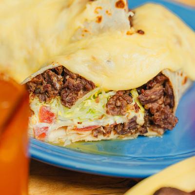 Cheese-covered burrito cut in half.