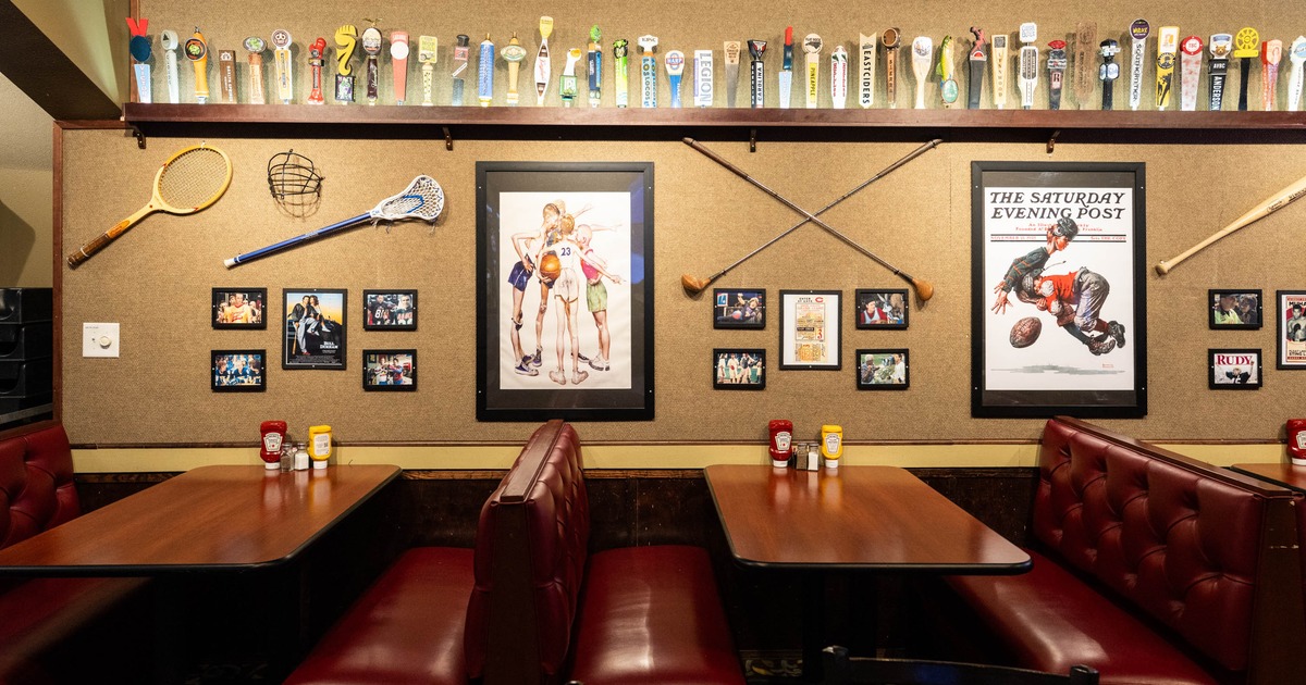 Restaurant booth with sports memorabilia and framed art on the wall, decorated with vintage sports equipment