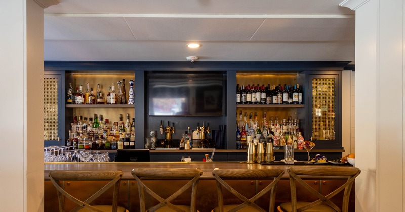 Interior of a bar with a well-stocked liquor shelf, and wooden stools