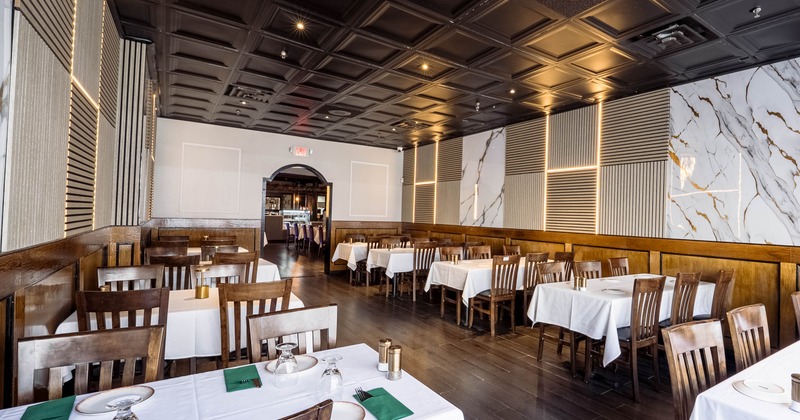 Modern restaurant interior with wooden tables and chairs, white tablecloths, decorative walls