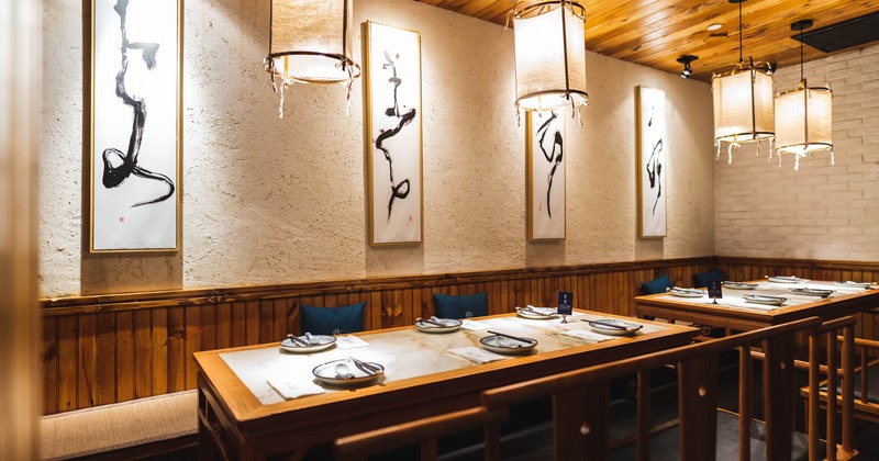 Interior, banquette bench, two tables for six ready for guests, Chinese style paintings on the wall